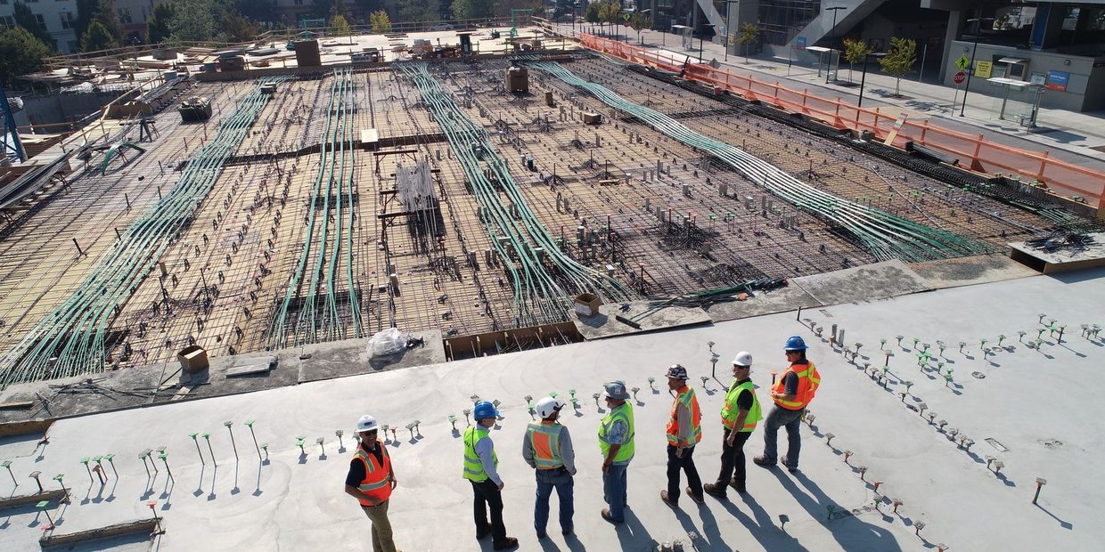 Baustelle mit Bewehrung fuer eine Bodenplatte, Bauleute im Hintergrund