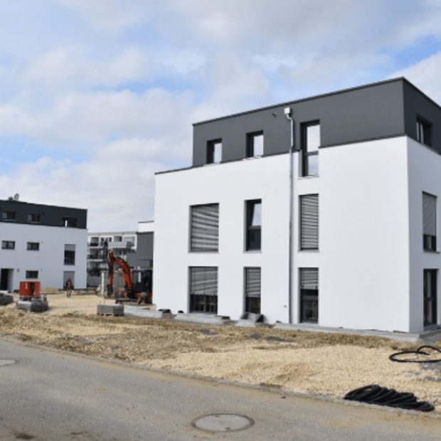 Mehrfamilienhaus im Bau mit Baumaschine davor
