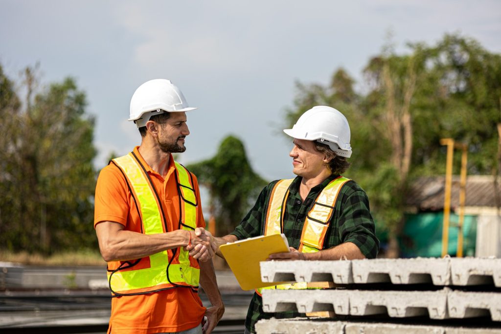 Zwei Bauleute geben sich auf der Baustelle die Hand